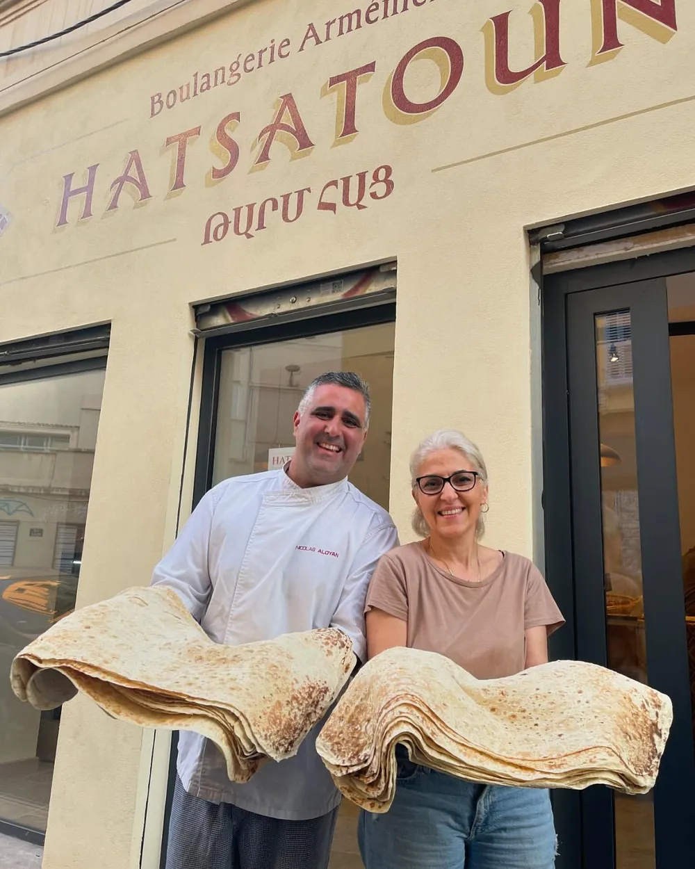 Deux membres de la famille Harutyunyan devant la boutique, un lavash dans les bras